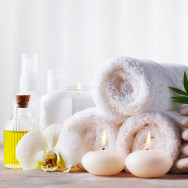 Spa, beauty treatment and wellness background with massage pebbles, orchid flowers, towels, cosmetic products and burning candles. Copy space for text.